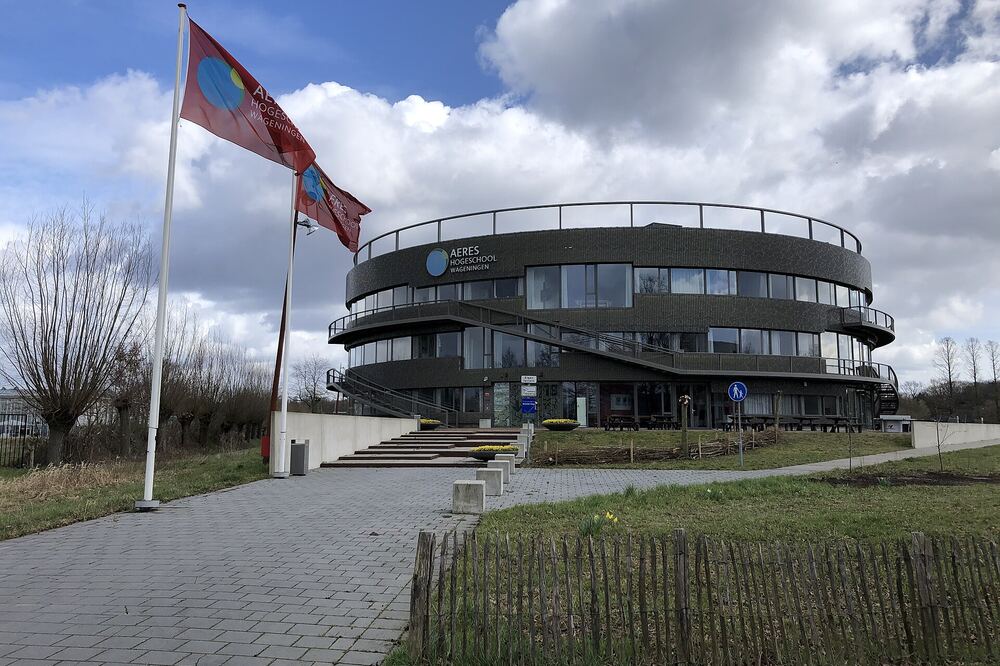 Het gebogen gebouw van de Aeres Hogeschool in Wageningen met vlaggen ervoor