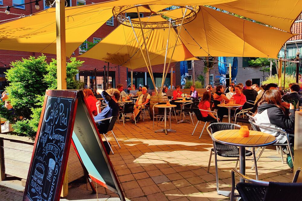 Het zonnige terras van de Stadsbrouwerij in Wageningen met gele parasols